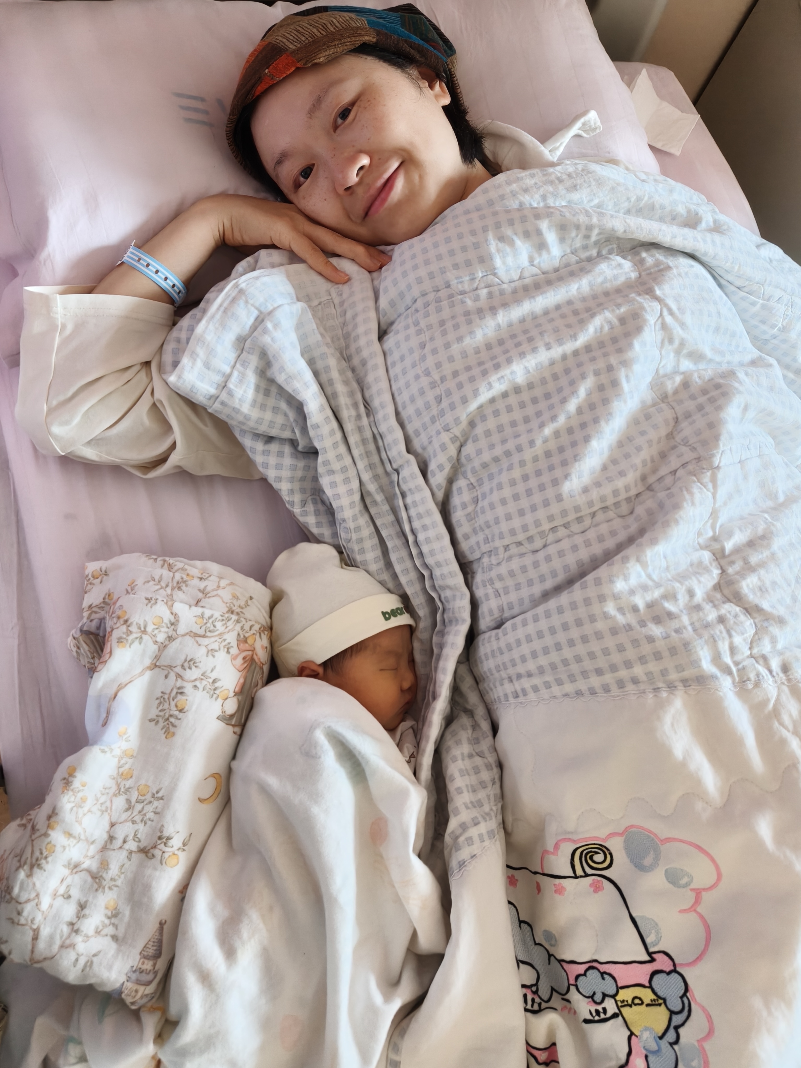 妈妈躺在病床上温柔地陪着刚出生的宝宝
